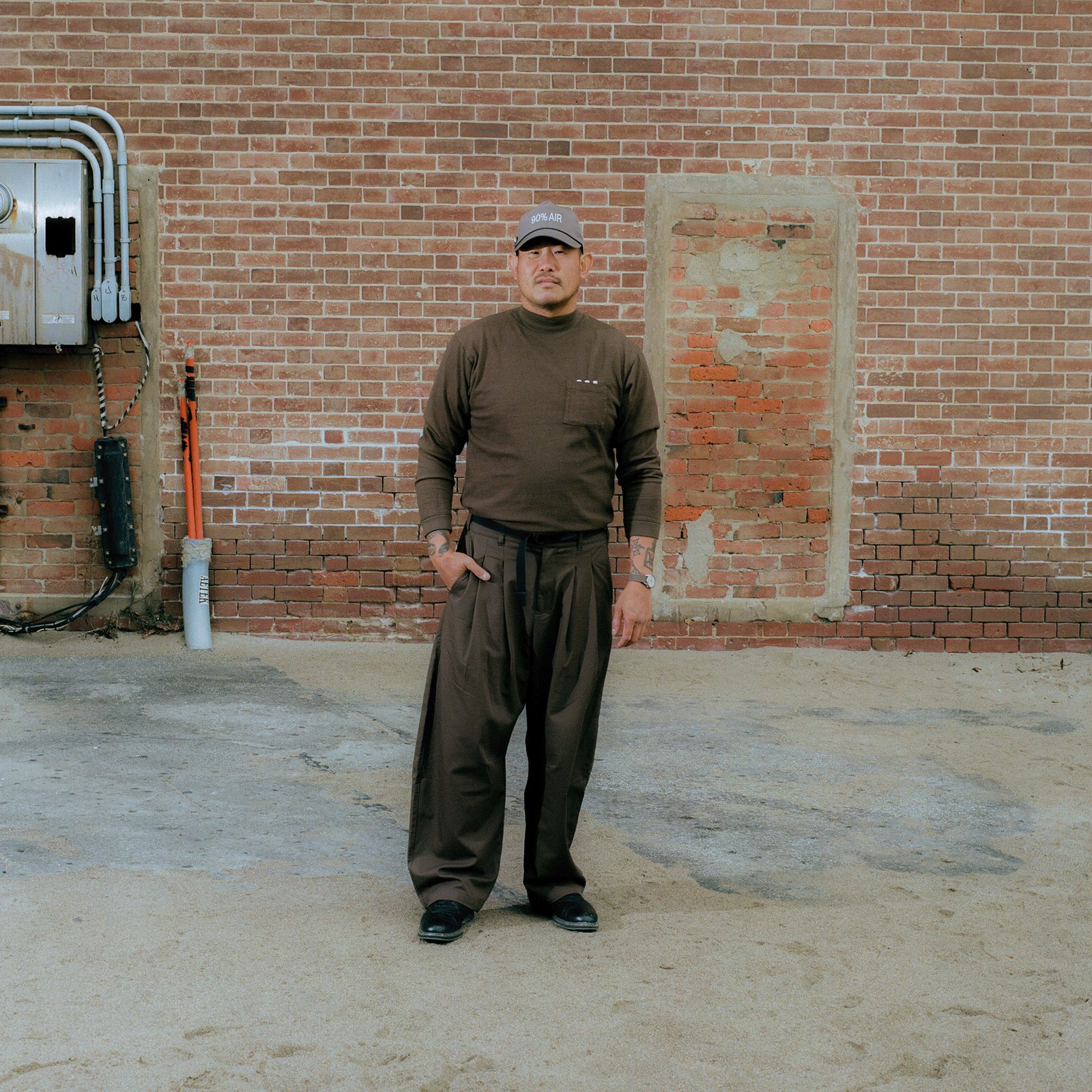 The L/S Work Shirt in Earth worn against a brick wall