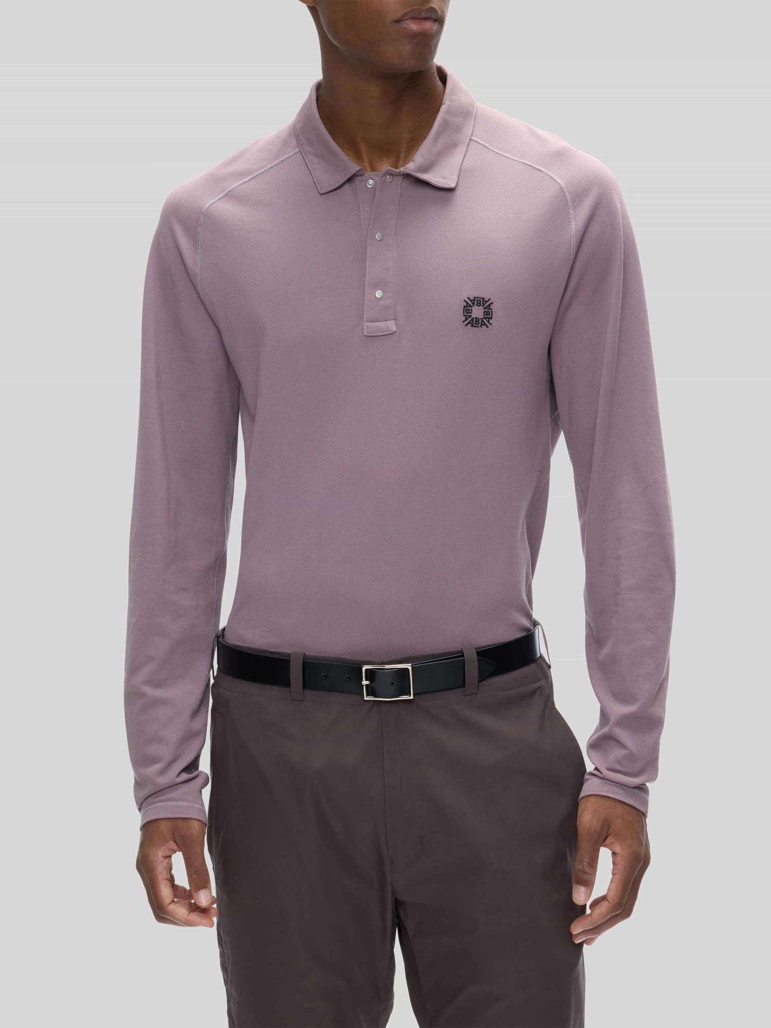 The mauve Voar long-sleeve polo tucked into mud trousers with a black belt