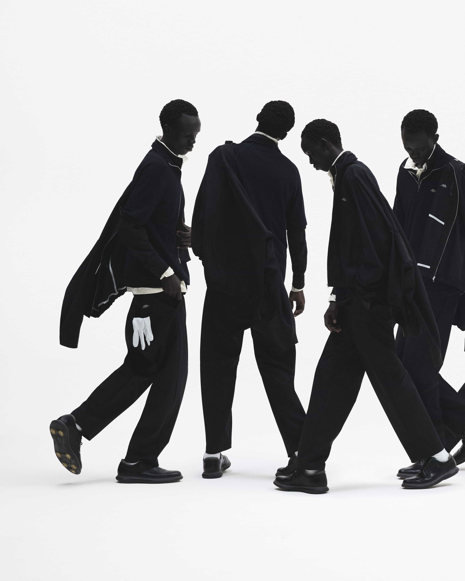 Alba Golf campaign: a line of models walking in dark layers with white golf gloves