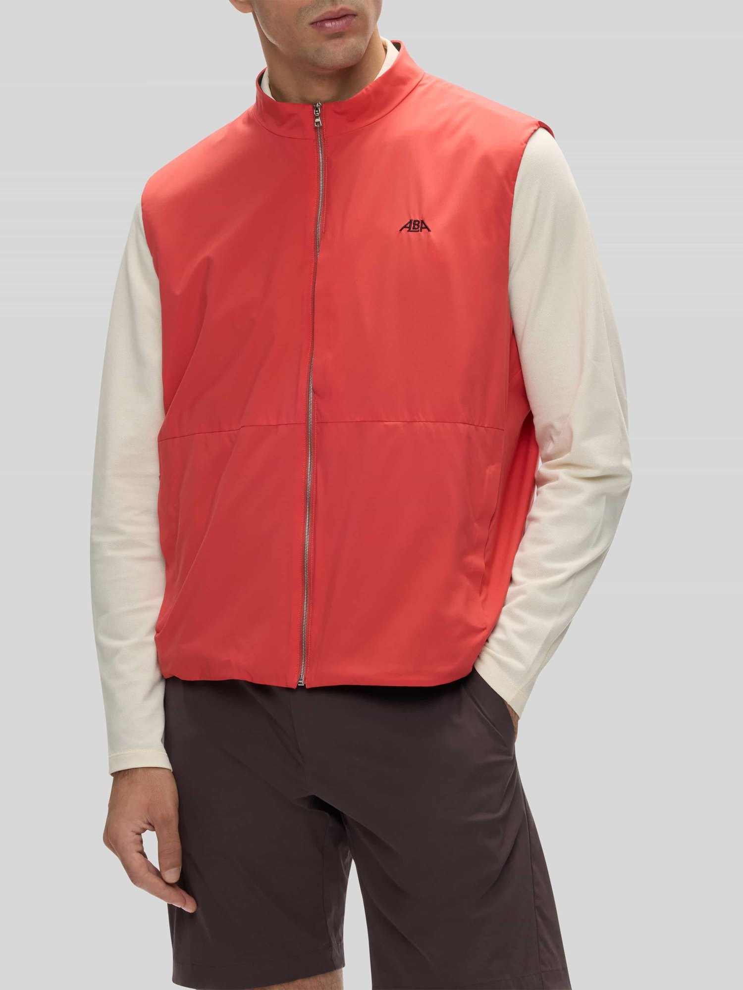 The salmon Glen Padded Vest over an ivory long-sleeve polo