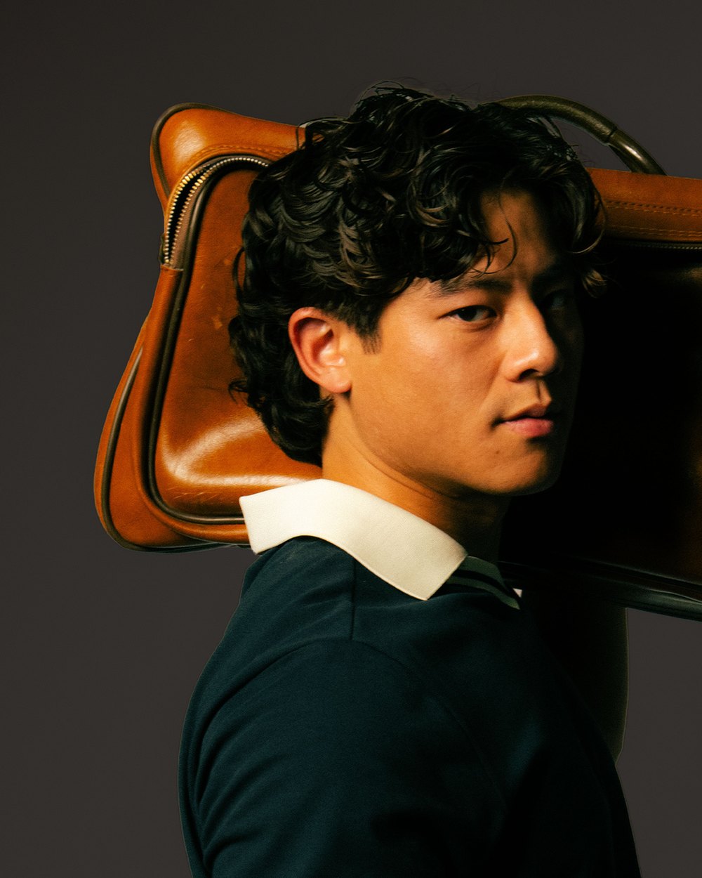 Kingfisher Golf campaign photo: a man carrying a vintage leather bag on his shoulder