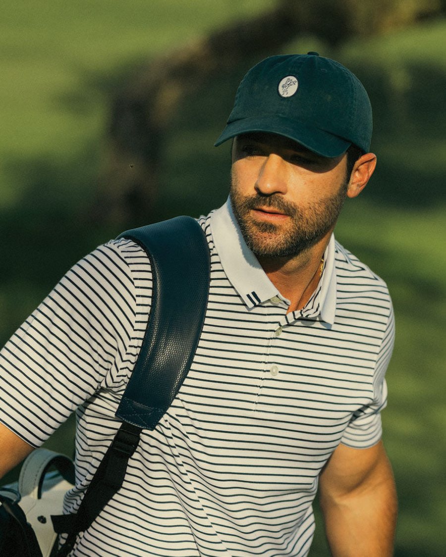 A golfer in a striped Ashworth polo carrying his bag