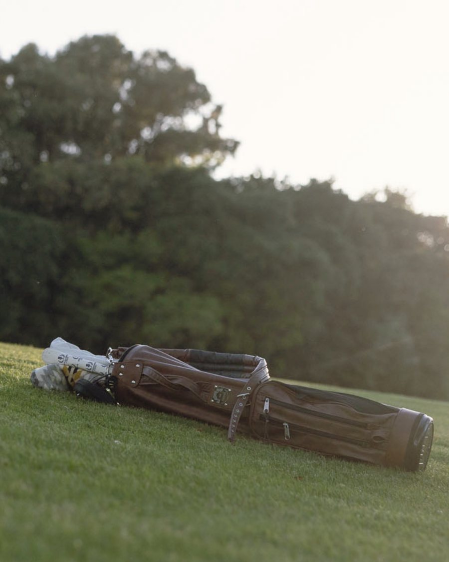 An Ashworth carry bag lying on the grass under trees