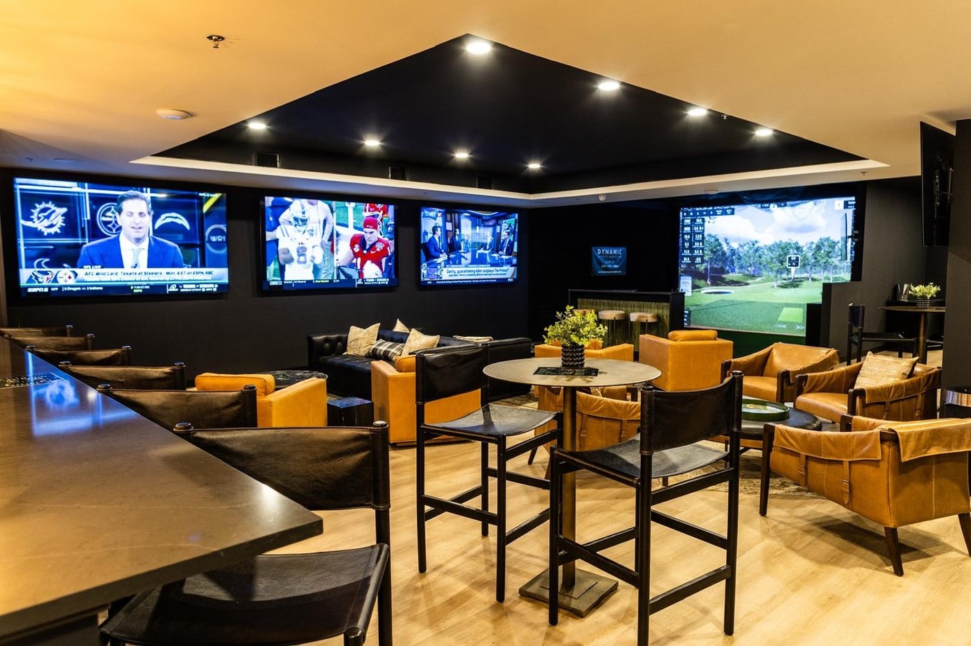 The bar and lounge at 1872 Golf Club in Georgetown, with screens above the stools