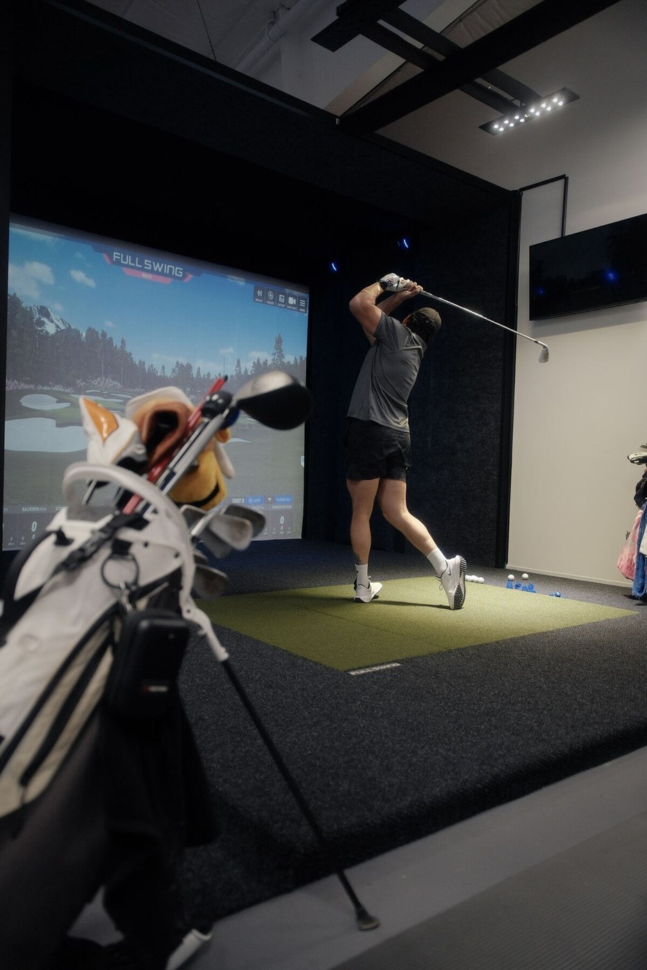 A golfer mid-swing in the bay at Austin Indoor Golf