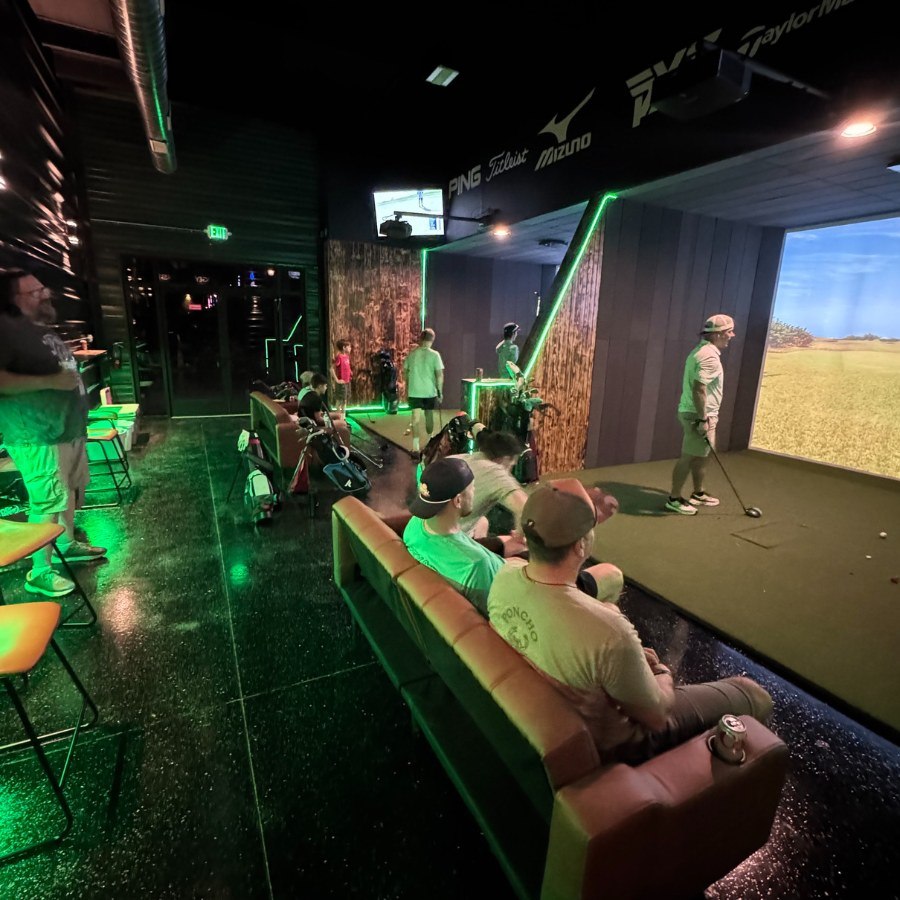 Green-lit simulator bays with players at Bogey Master in Hutto