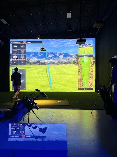 A TrackMan iO bay at Fiber Golf lit up against the 40-foot impact screen