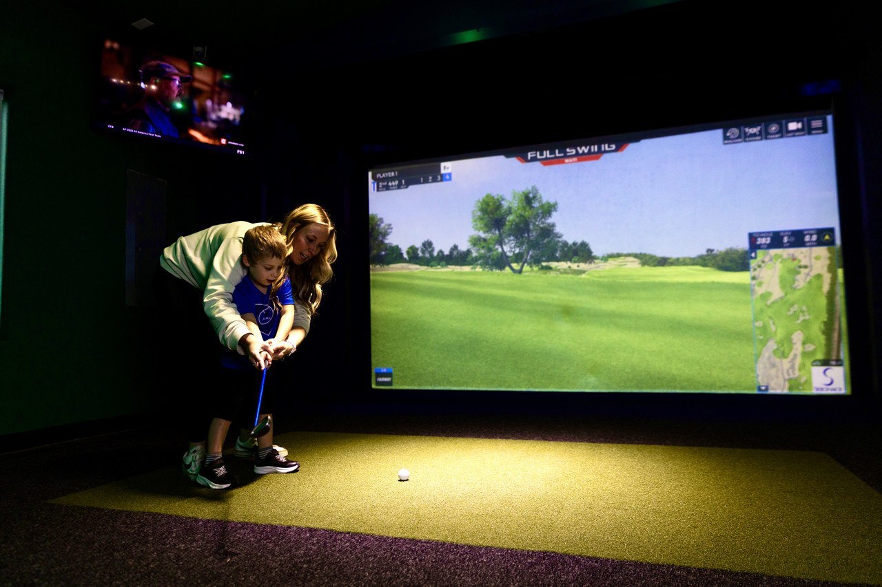 Two players in a bay at Swing Station, one mid-swing