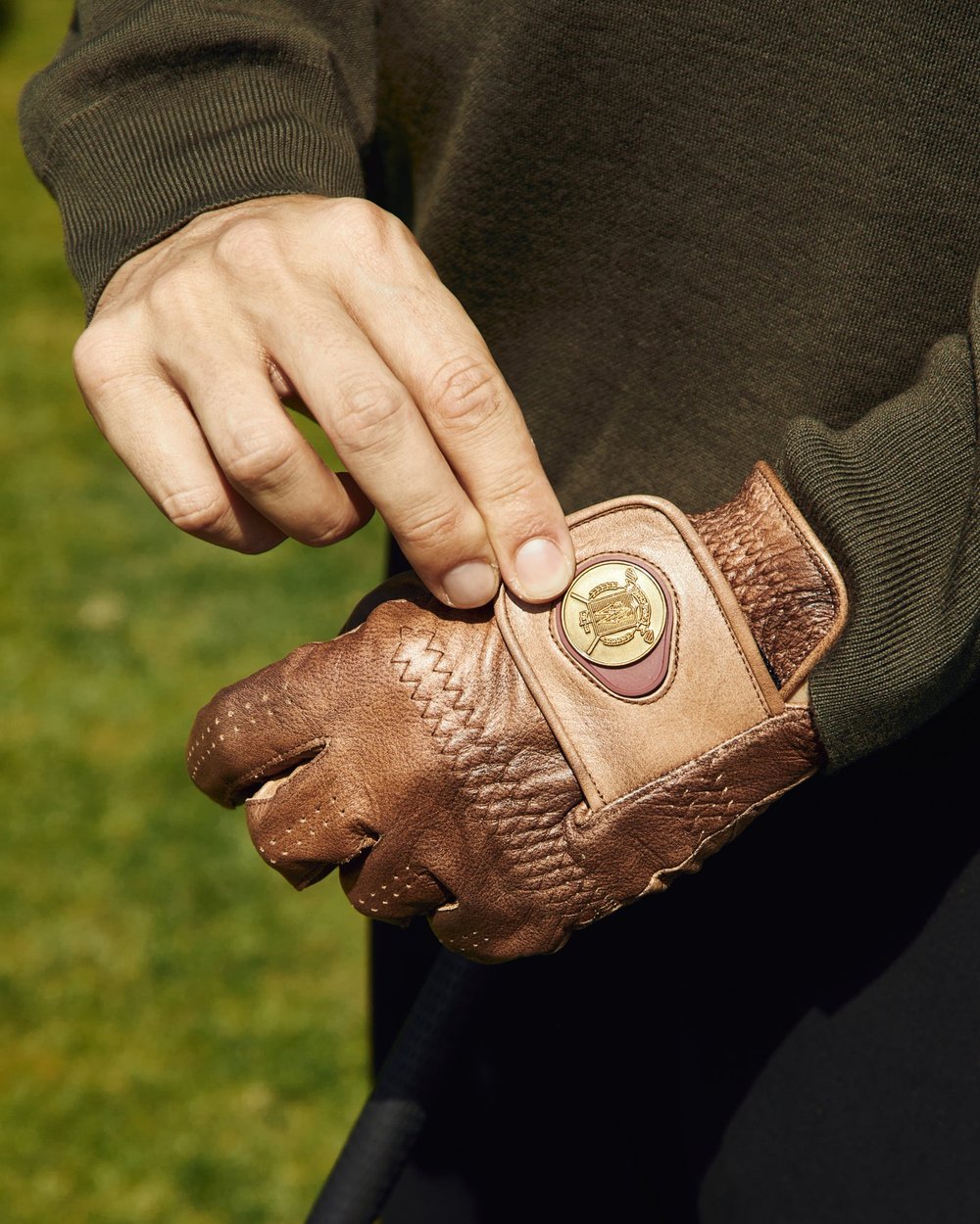 A hand pulling on a brown houndstooth Modest Vintage Player glove