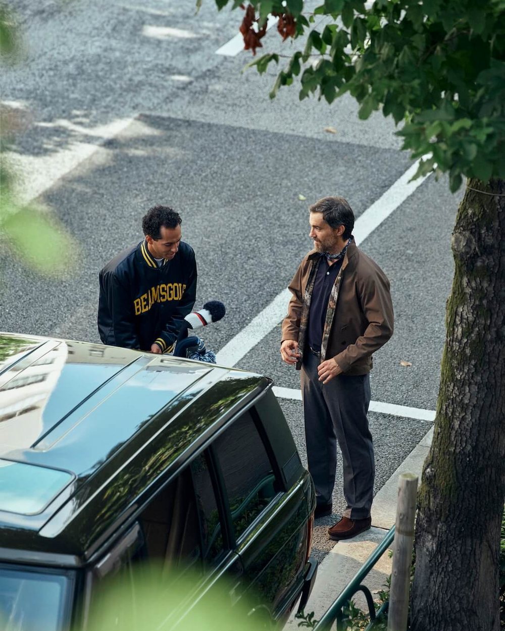 Two men talking by a vintage car on a city street, one in a navy BEAMS GOLF jacket