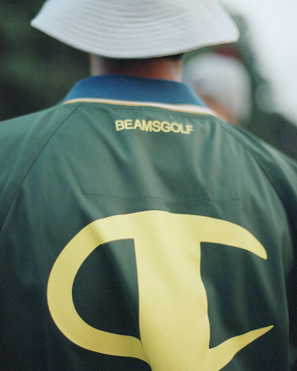 The back of a green BEAMS GOLF jacket with a large yellow Champion C