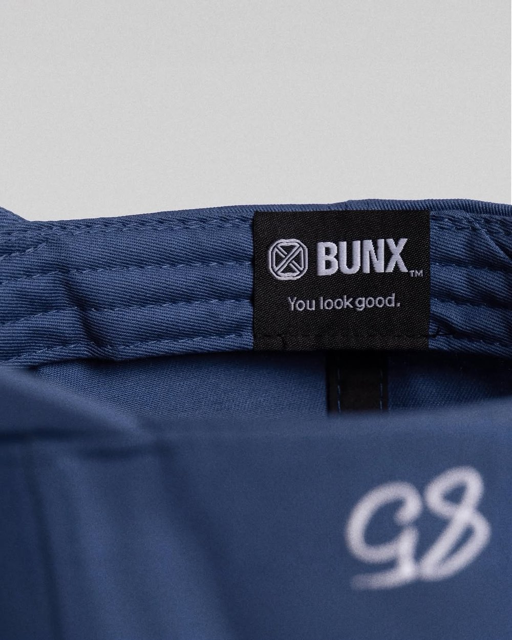 The woven label inside a blue BUNX hat reading You look good.