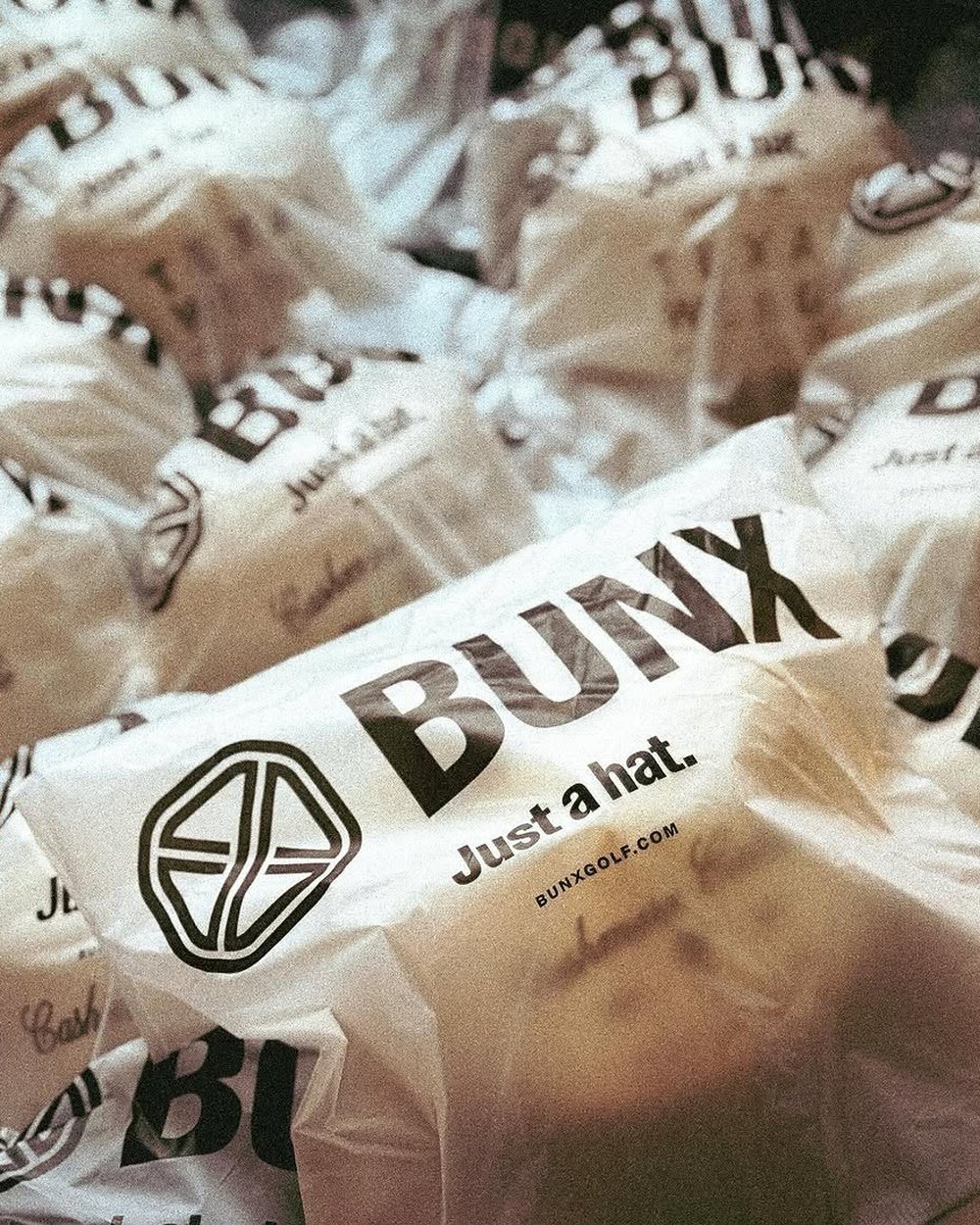 A pile of BUNX bags printed Just a hat.