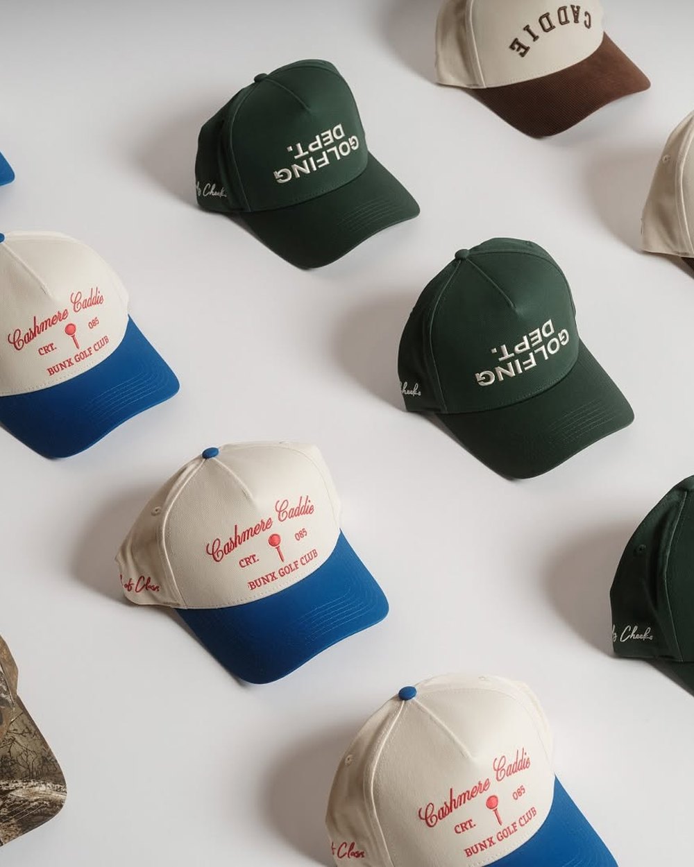 Cashmere Caddie and Golfing Dept hats laid out on a white table