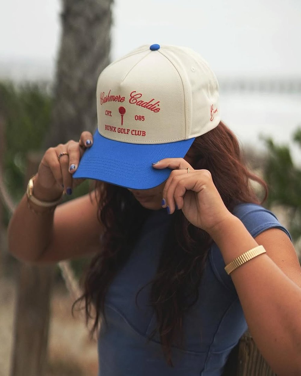A woman pulling down the brim of a Cashmere Caddie hat