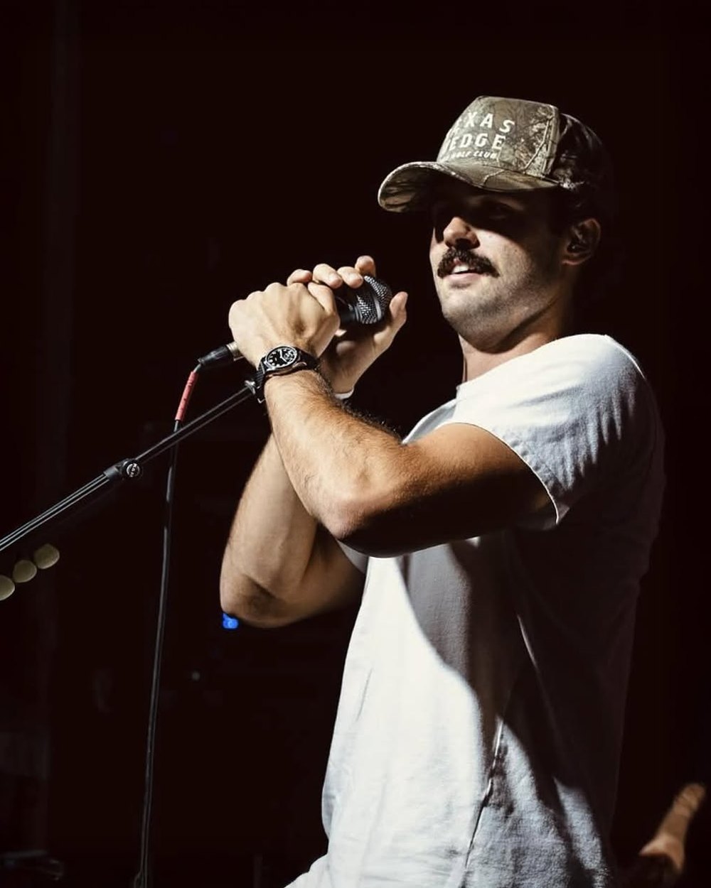 Musician Clayton Mullen singing on stage in the camo Tex