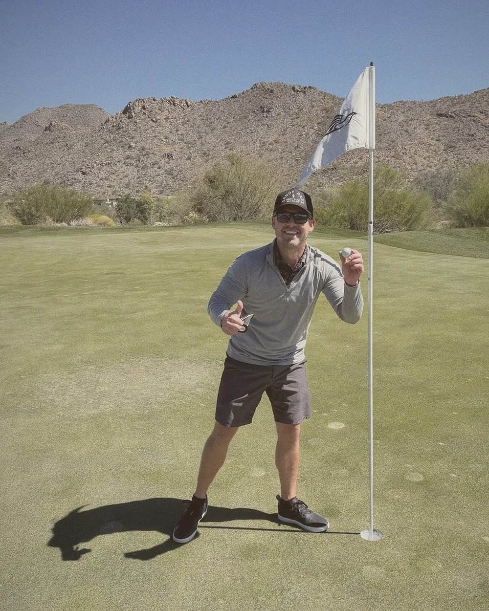 A golfer celebrating by the flag on a desert course