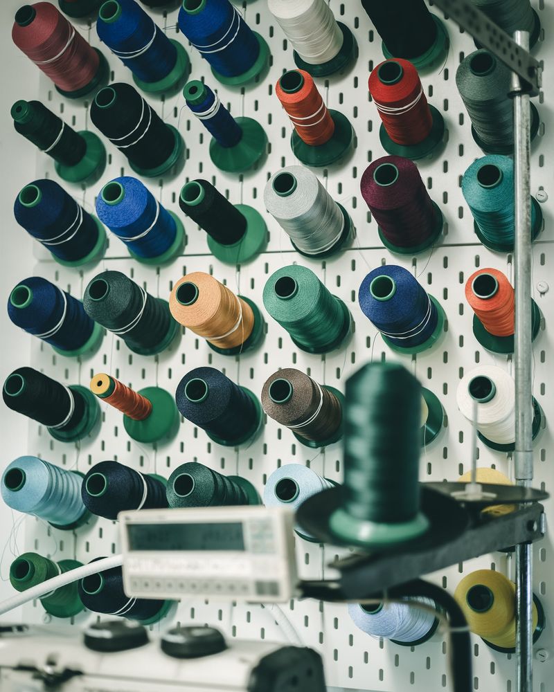 Spools of embroidery thread on a pegboard wall in the workshop