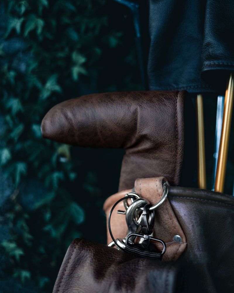 A brown leather cover and bag in front of ivy
