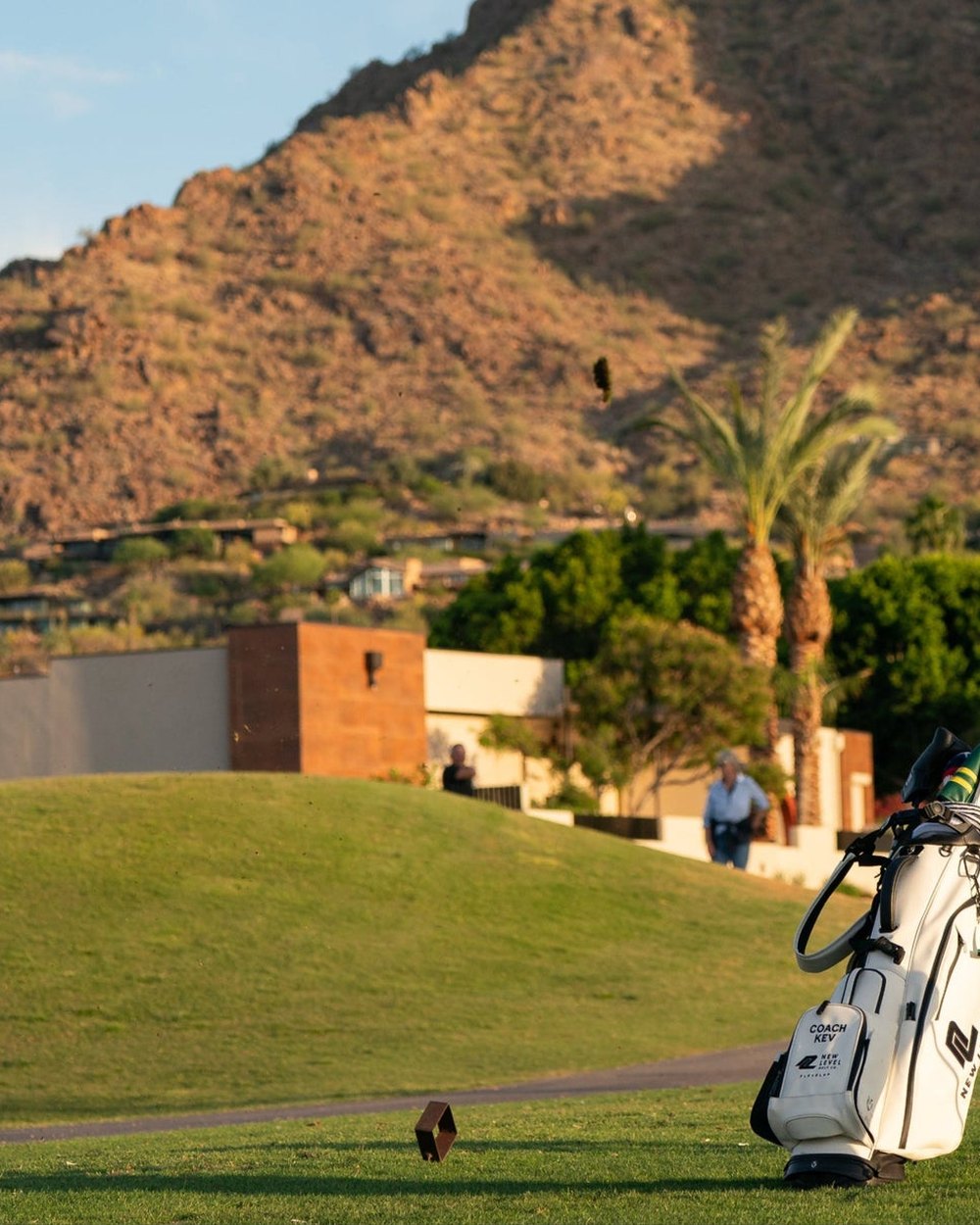 A golf bag on a course below desert mountains