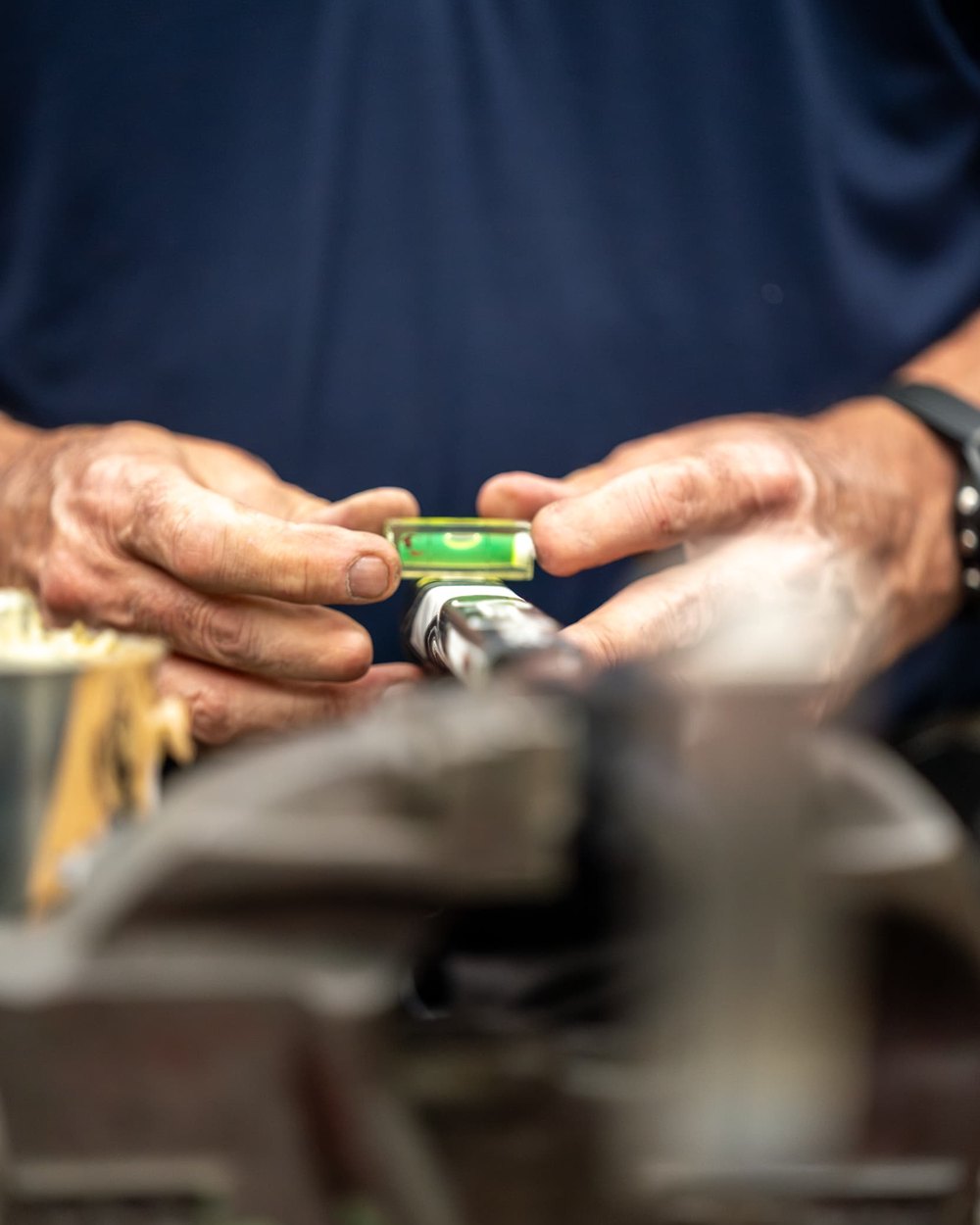 Hands checking a putter head with a level in a vise