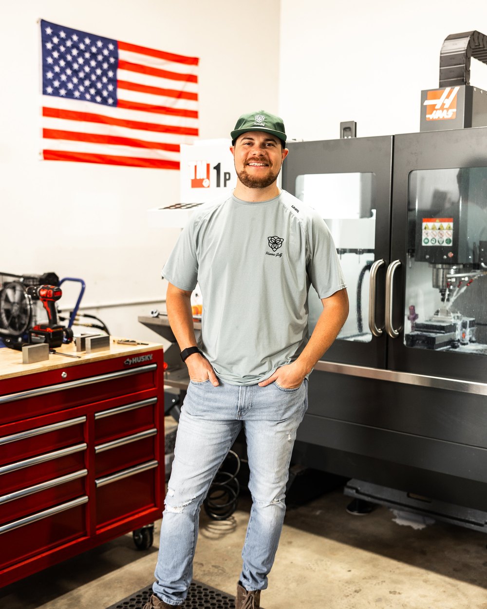 A Hanna Golf maker standing in front of CNC mills and a toolbox