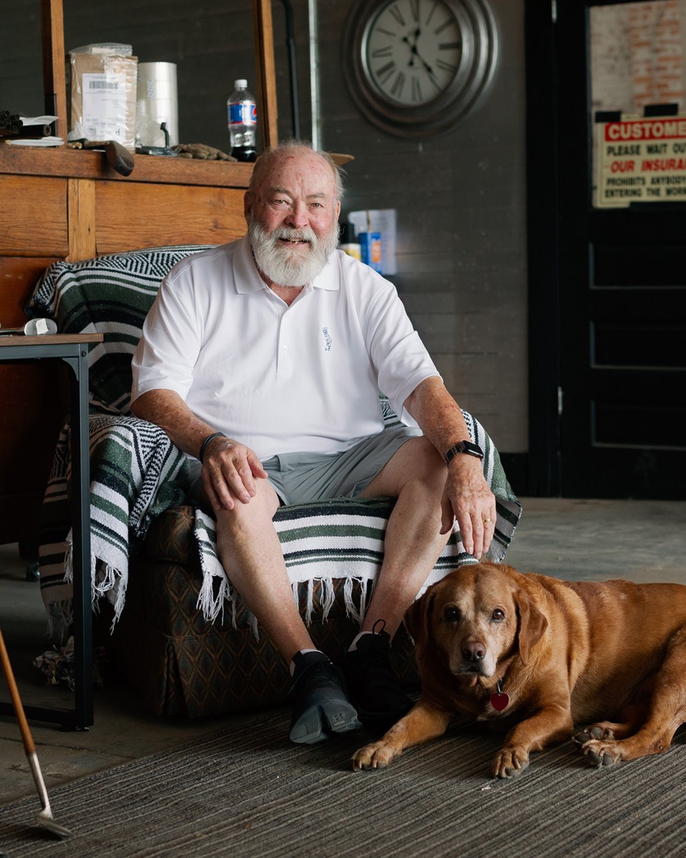 Tad Moore sitting in his workshop with his dog