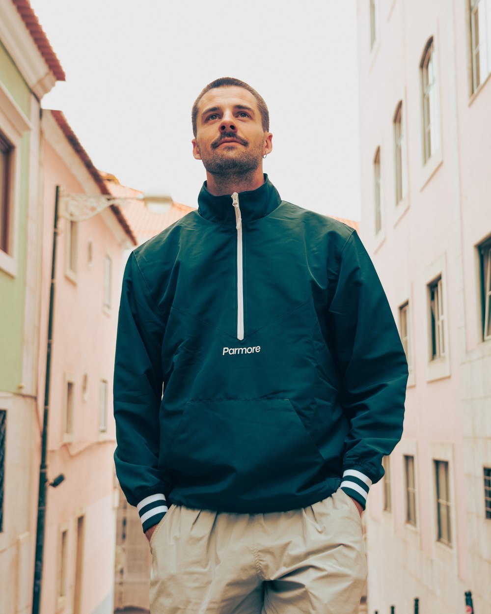 A man in Parmore's forest green Varsity Quarter-Zip on a city street