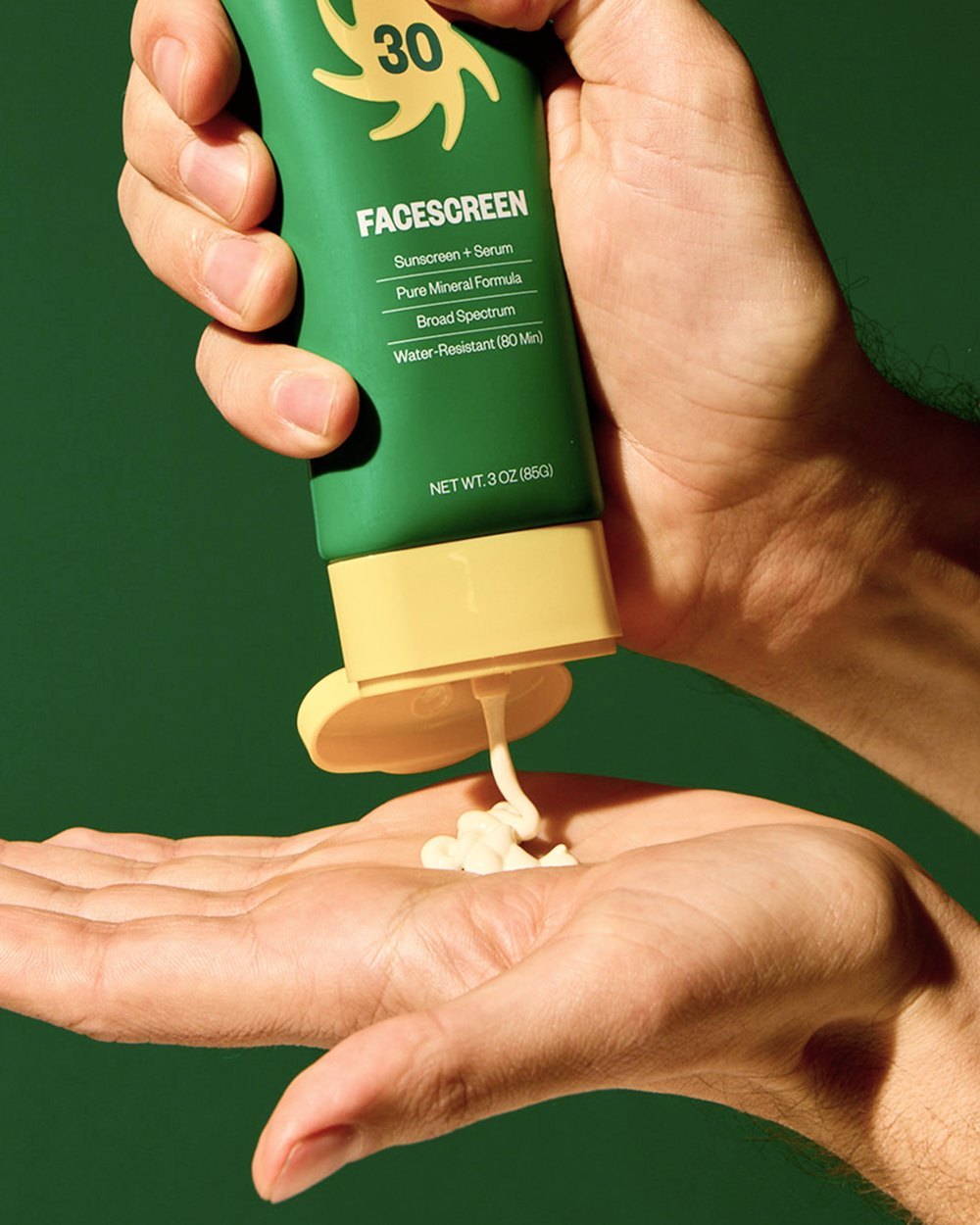 A hand holding Lazyface's green Facescreen on a green background