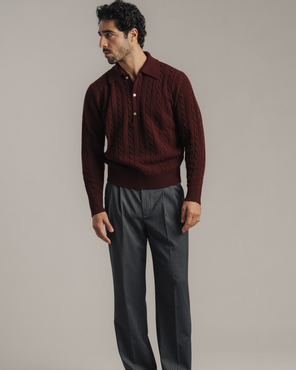 A model in Late Nine's burgundy cable knit polo and grey slacks