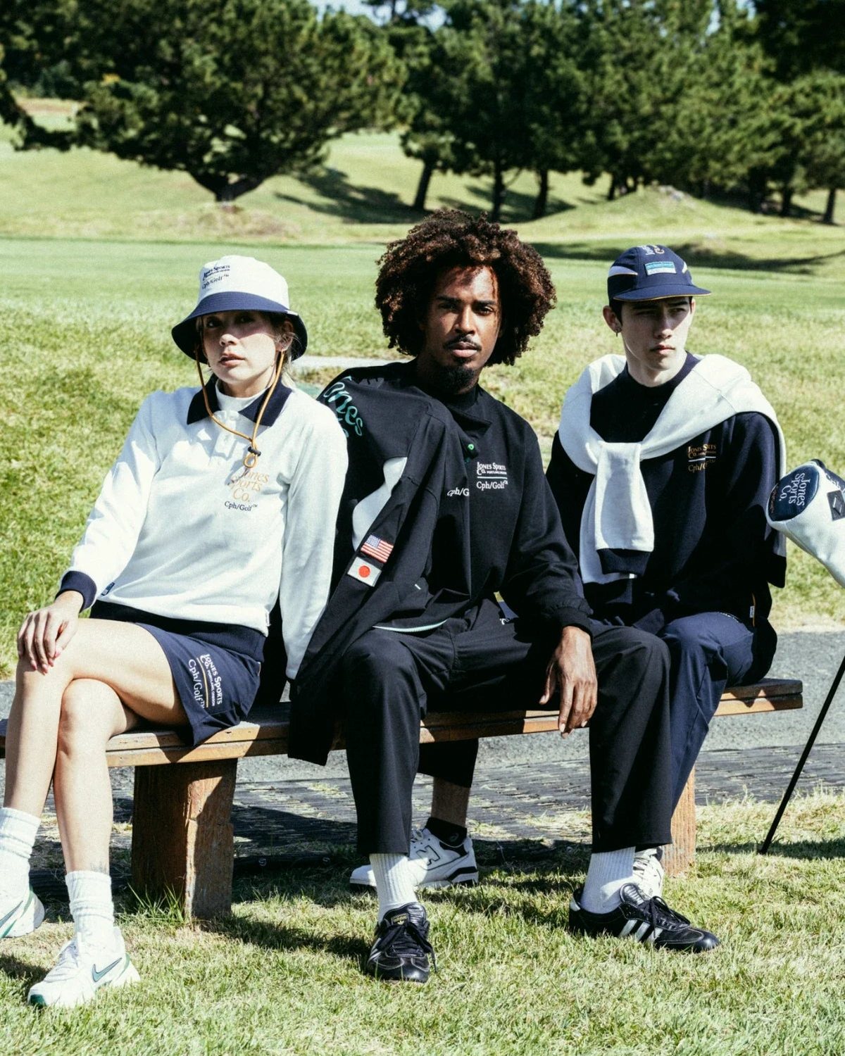 Three players in the Jones and Cph/Golf collaboration sitting on a bench by the course