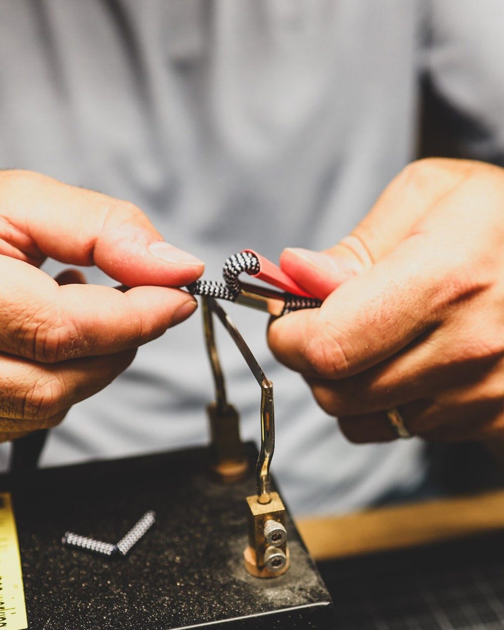 Hands assembling a Dimple & Divot brush and its tether at a workbench