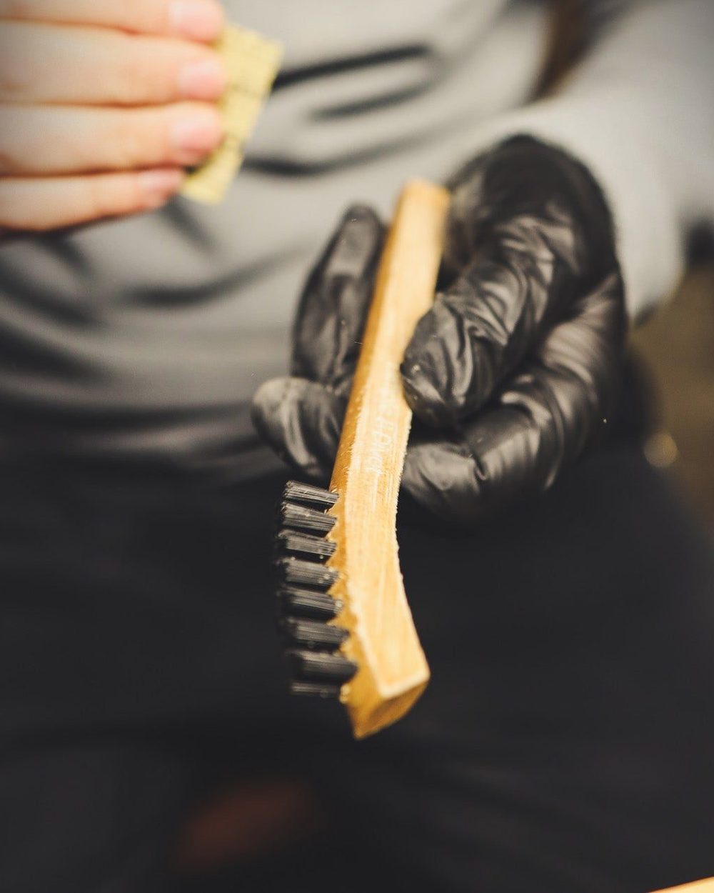 A gloved hand holding a hickory brush handle during sanding