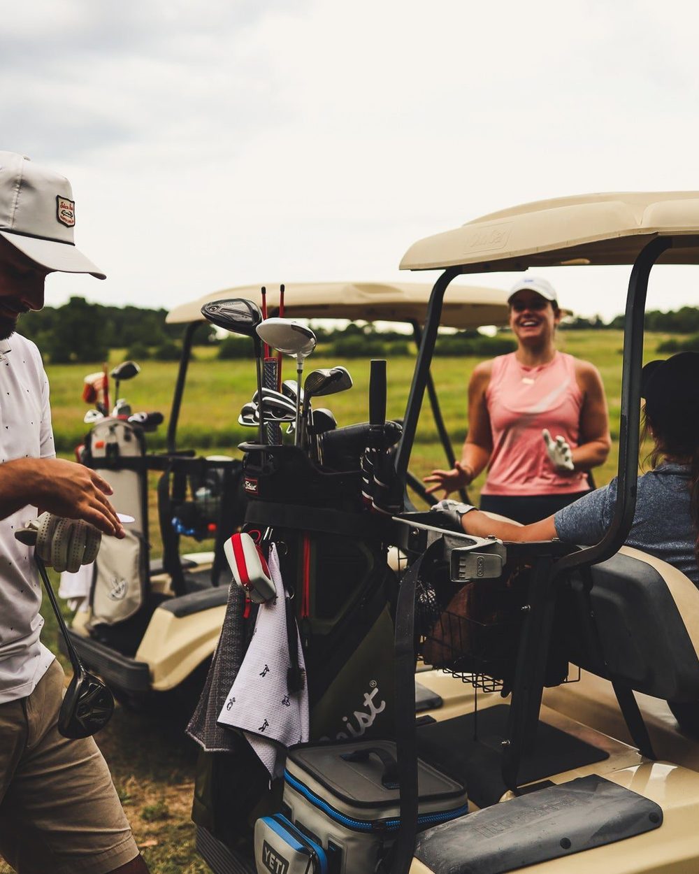 Golfers laughing around a golf cart on the course