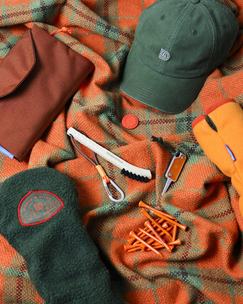 A flat lay of the In The Woods collection on an orange plaid blanket