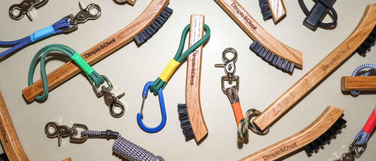 Dimple & Divot hickory brushes laid out on grey with their coloured tethers, carabiners and nickel snaps