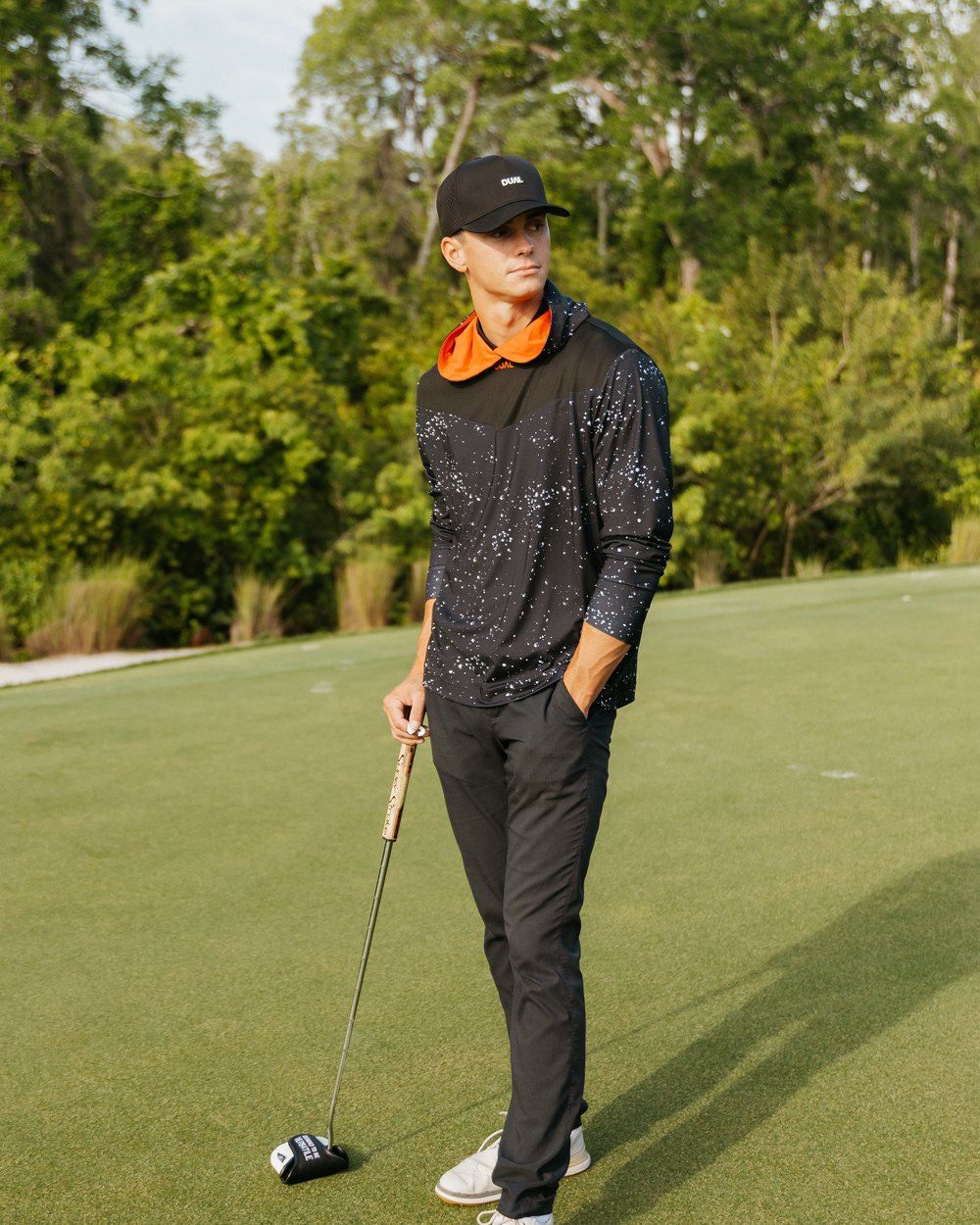 A golfer in a black speckled top lining up a putt with the black and white Dual mallet cover