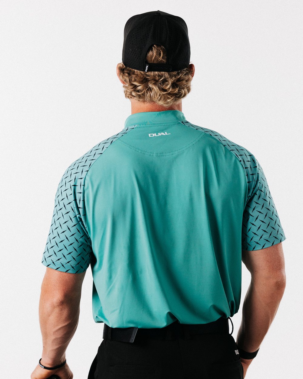 A man seen from behind in the green Diamond Blade polo with patterned raglan sleeves