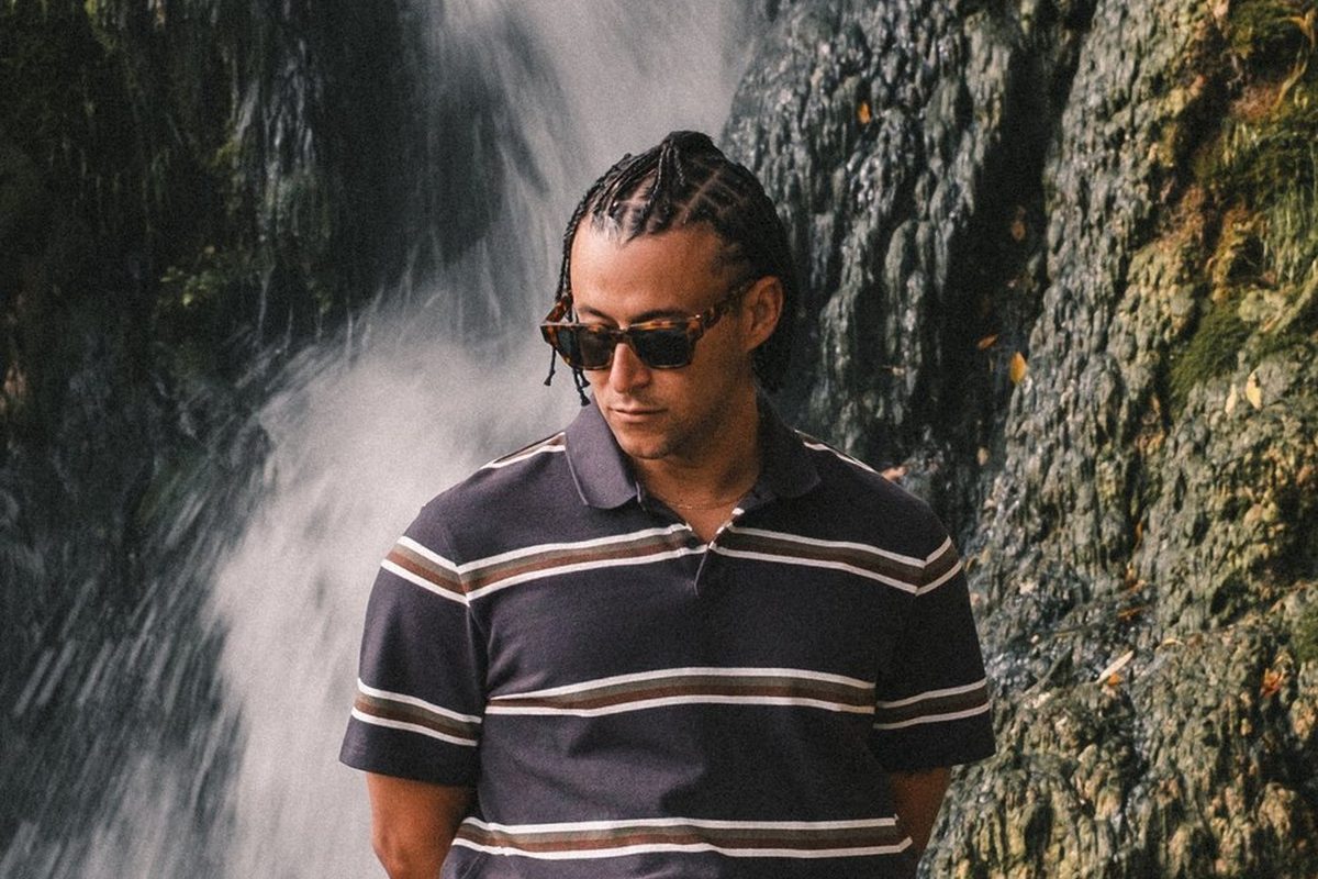 A man in a striped Gumtree polo standing in front of a waterfall