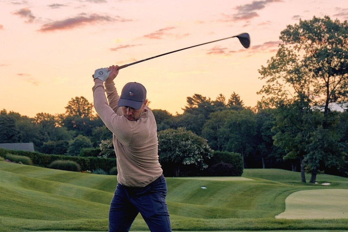 A golfer finishing his swing at sunset in Rookline