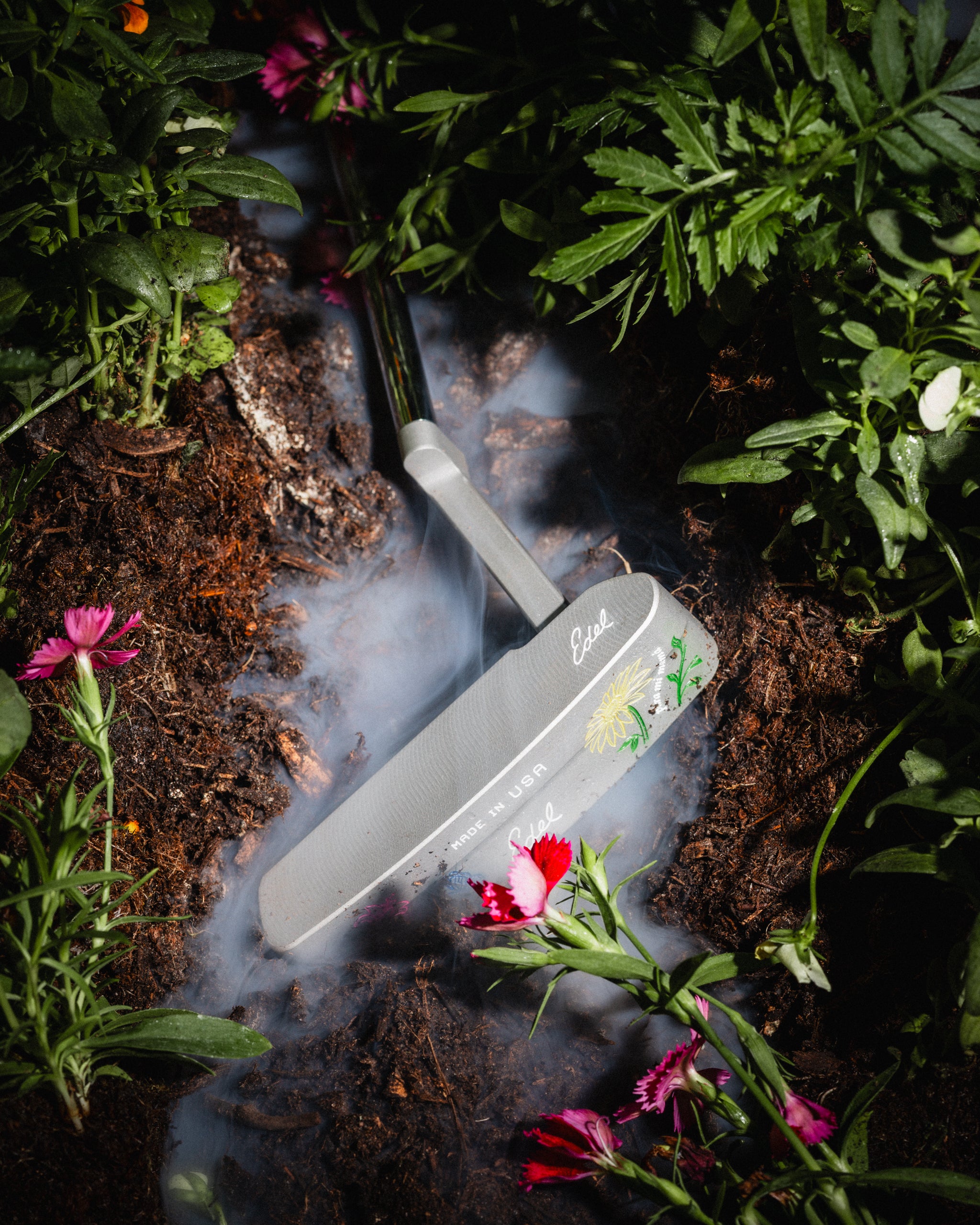 The Bloom putter in a flowerbed under drifting smoke