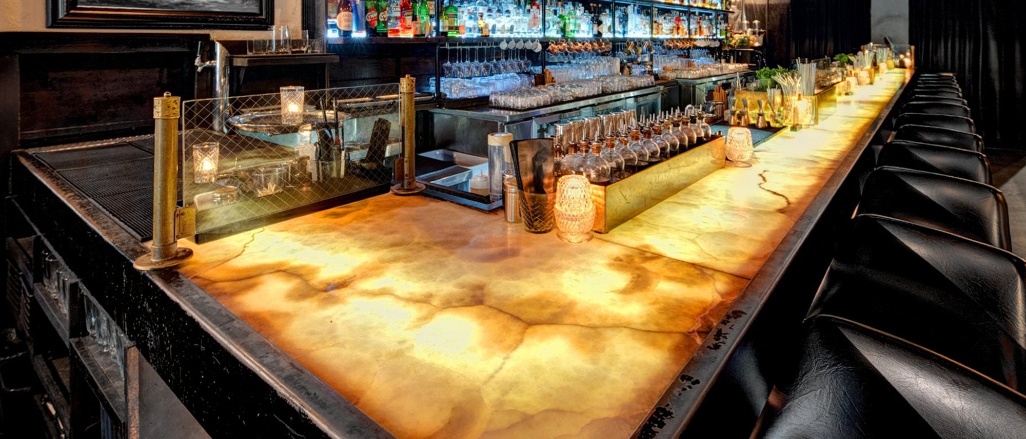 The main bar at The Roosevelt Room in downtown Austin, lit up in the evening