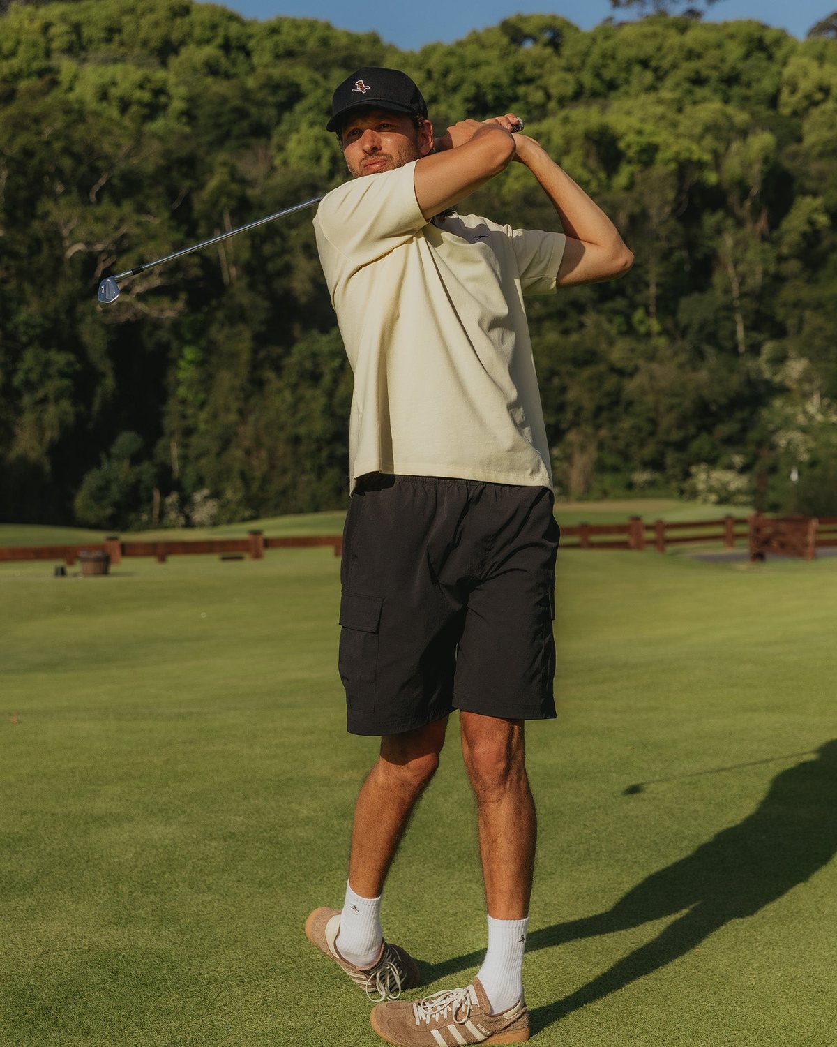 A golfer swinging in Walker black ripstop cargo shorts