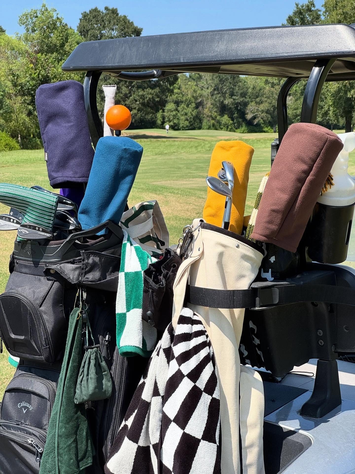 Loaded golf cart with bags and brightly coloured headcovers stacked in the back
