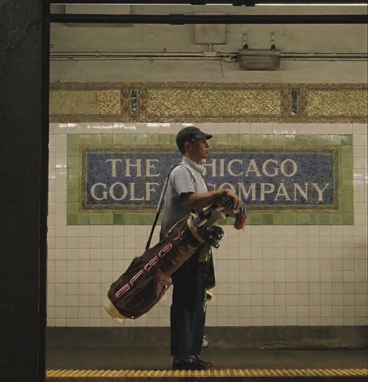 Golfer carrying bag in subway station with Chicago Golf Company mosaic tile wall