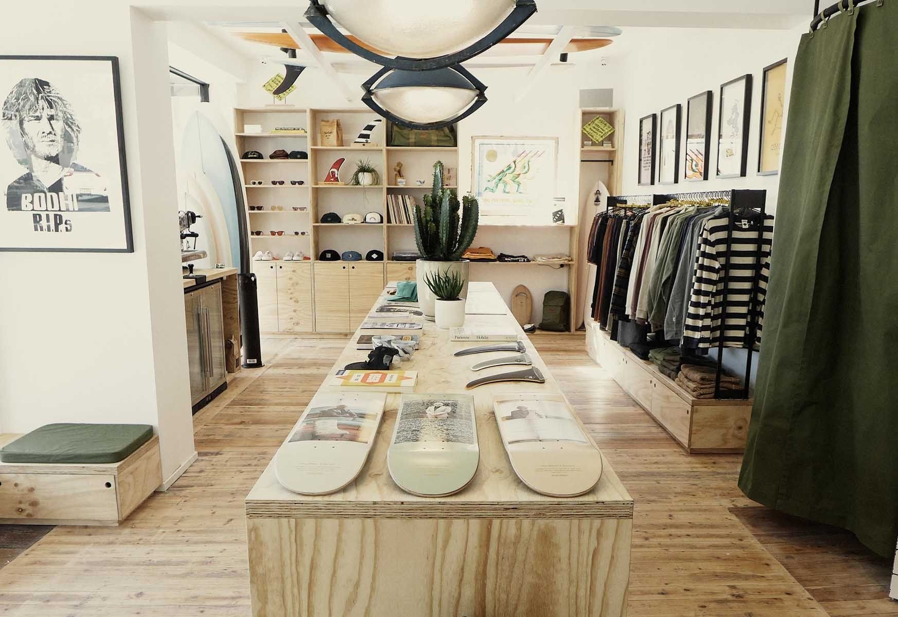 Shop interior with a pale wood counter, open shelving and a wall of framed prints