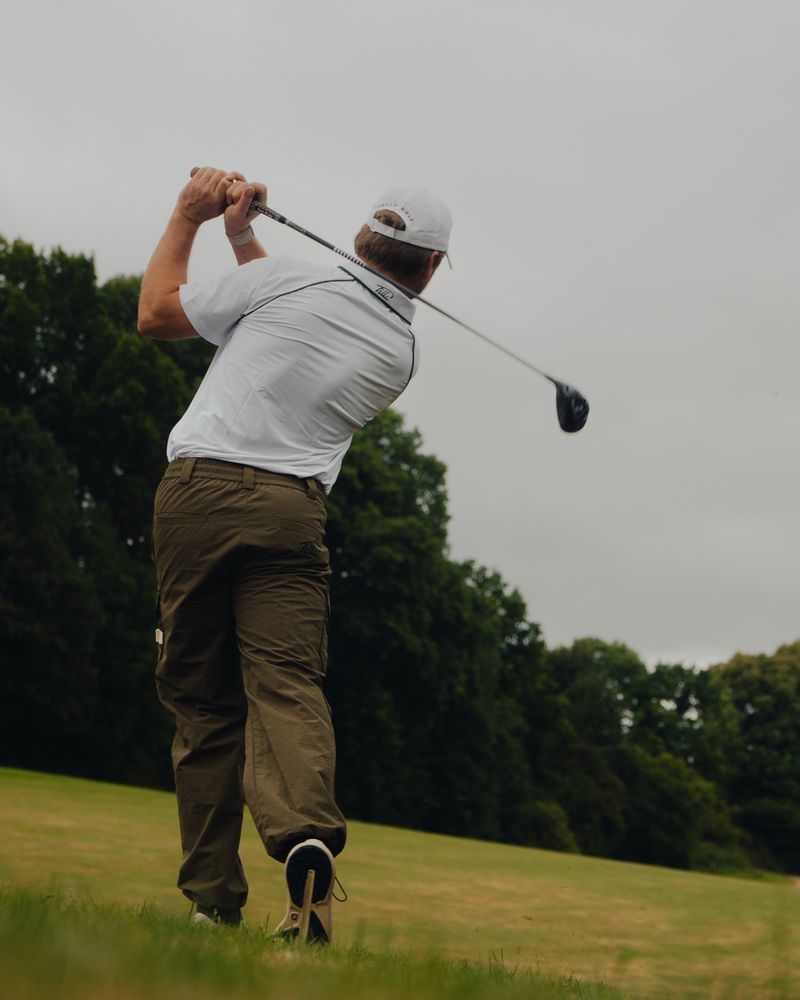 A golfer mid-swing in Fella's ripstop cargo pant