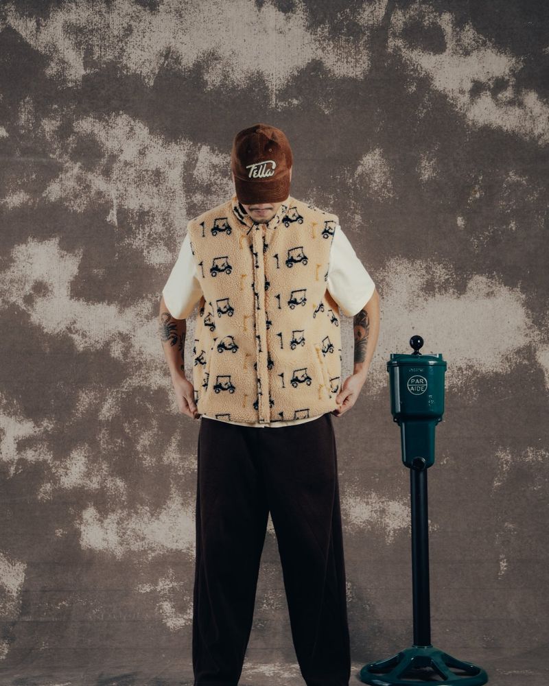 A model in the golf-cart sherpa bodywarmer standing beside a ball washer