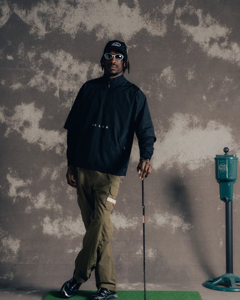 A model in the black Wyatt windshirt holding a club on a hitting mat