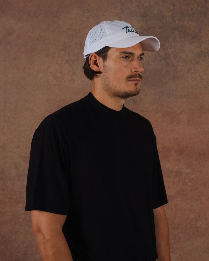 A model in a white Fella performance cap and a black mockneck